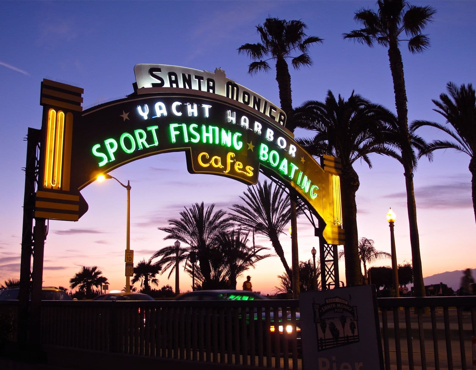 The lit-up entrance sign of the Santa Monica Pier at dusk
