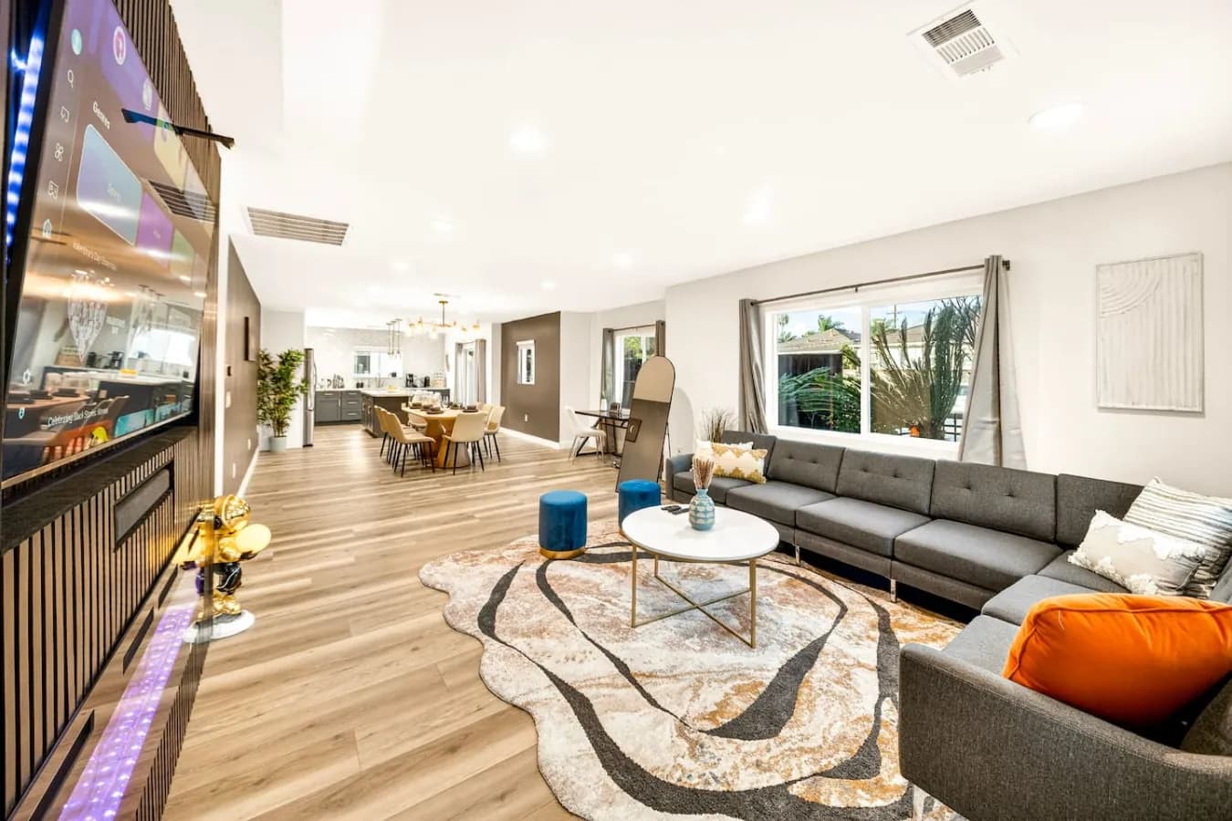 Open living room with a large grey sectional, rug and wood floors