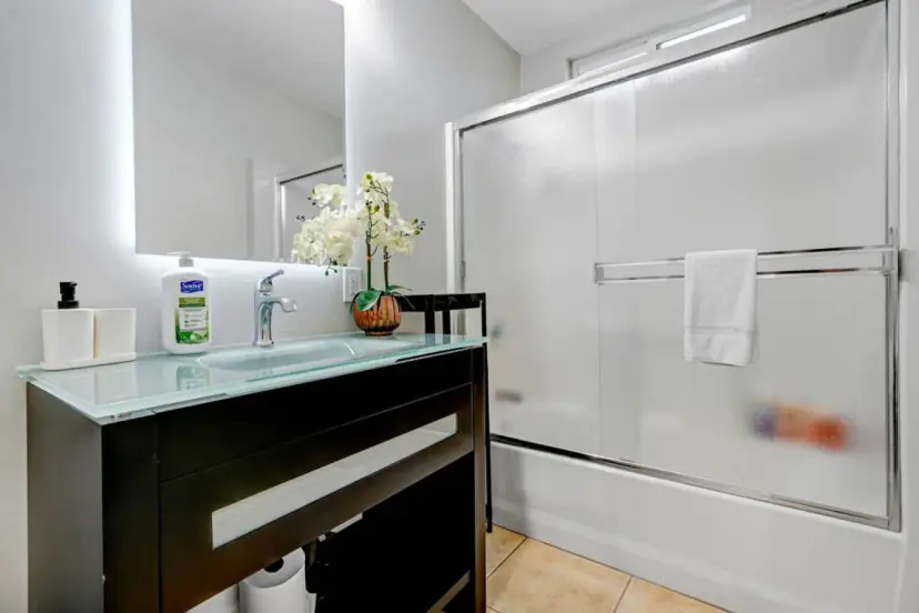 Bathroom with a lit mirror and a tub-shower