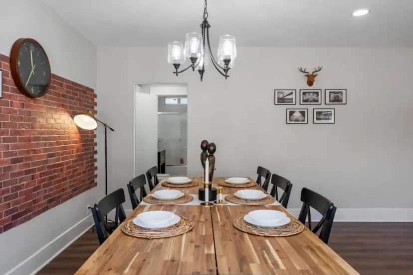 Butcher-block dining table beside a red brick feature wall
