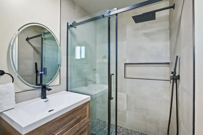 Walk-in glass shower and a round mirror
