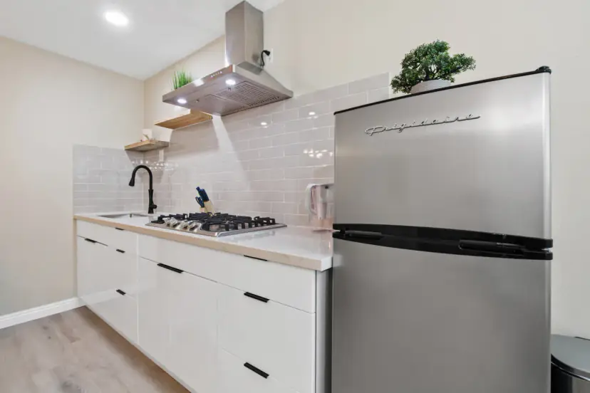 White kitchen with a gas cooktop and a fridge