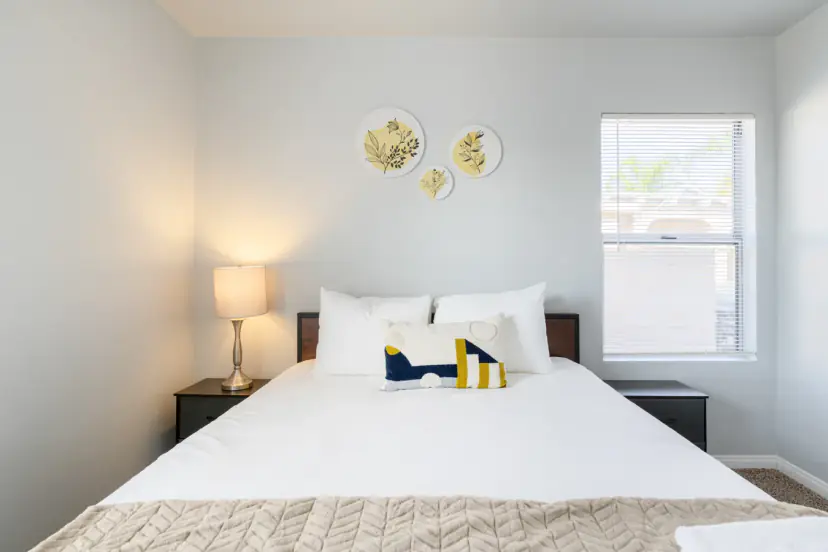 Queen bed with botanical wall plates and a window