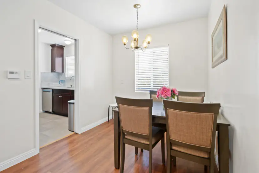 Dining table under a chandelier beside the kitchen