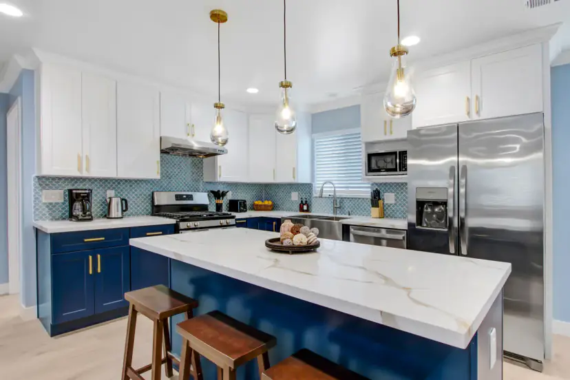 Navy island kitchen with a quartz top and pendants