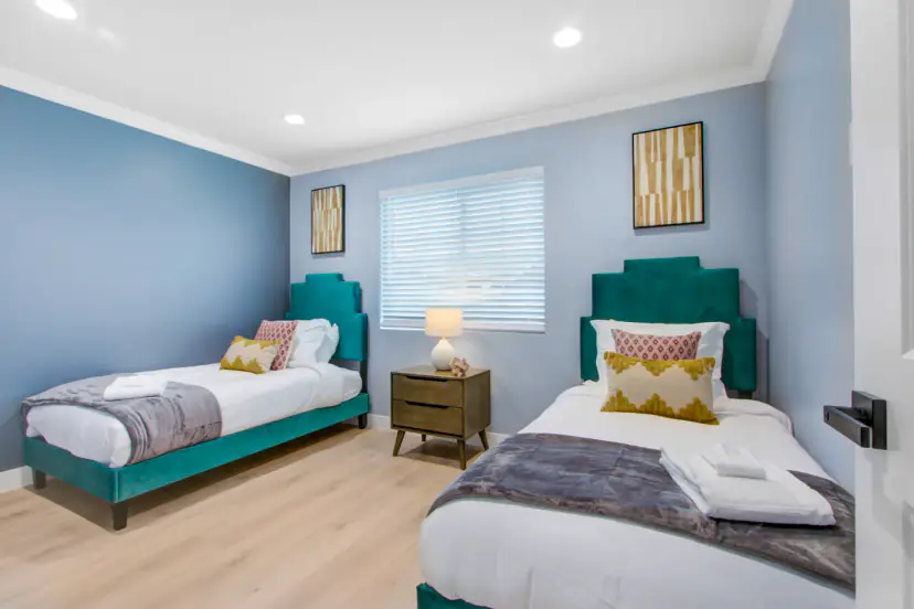 Two teal velvet twin beds under a window