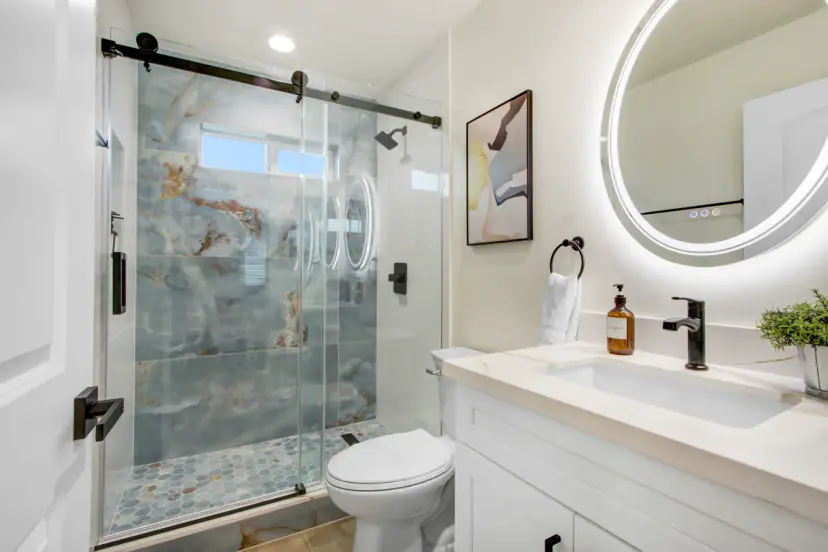 Bathroom with a blue marble shower and a lit mirror