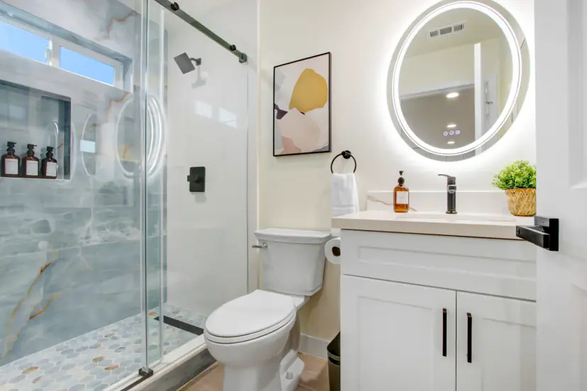 Bathroom with a glass shower and a round lit mirror