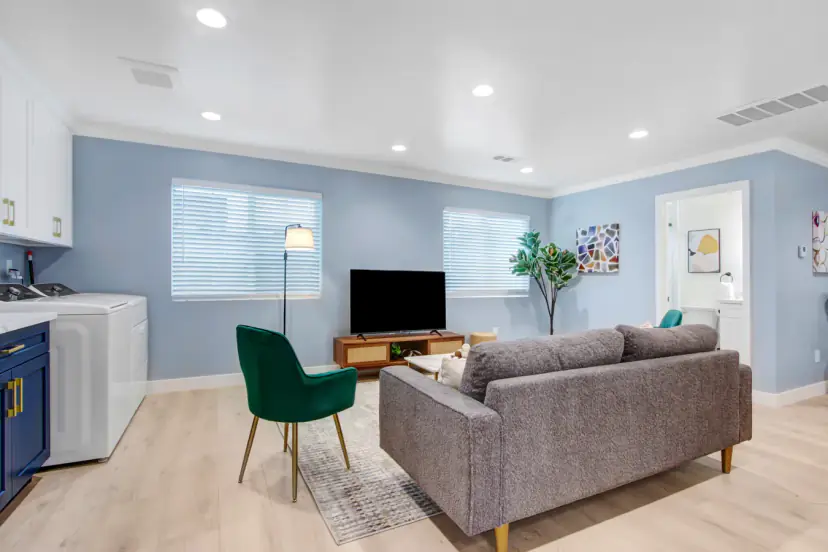 Living room with a grey sofa, TV and laundry corner