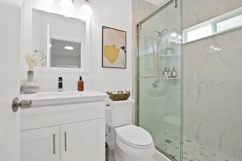 Bathroom with a marble-look shower and a white vanity