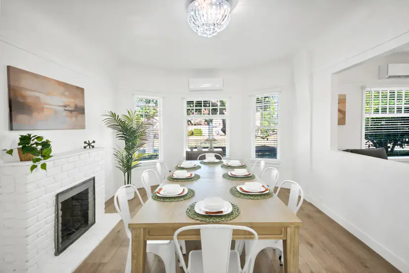 Dining table for eight by a white brick fireplace