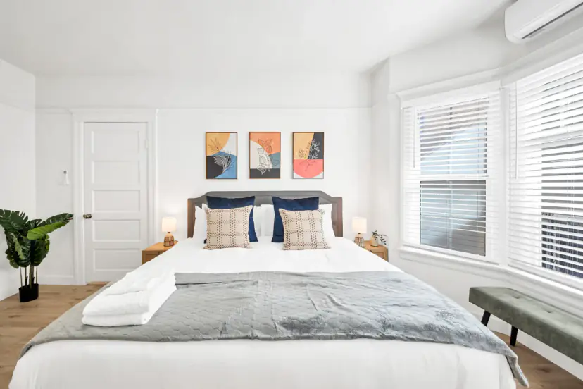 King bed with navy pillows and bay windows