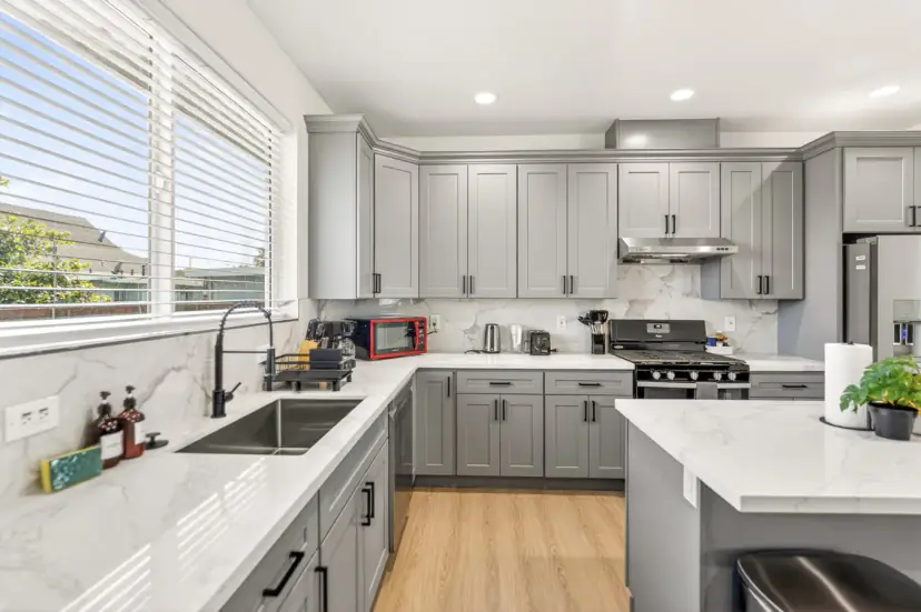 Grey shaker kitchen with quartz counters and a gas range