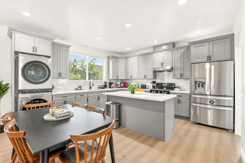 Dining table beside the kitchen island and a stacked washer and dryer