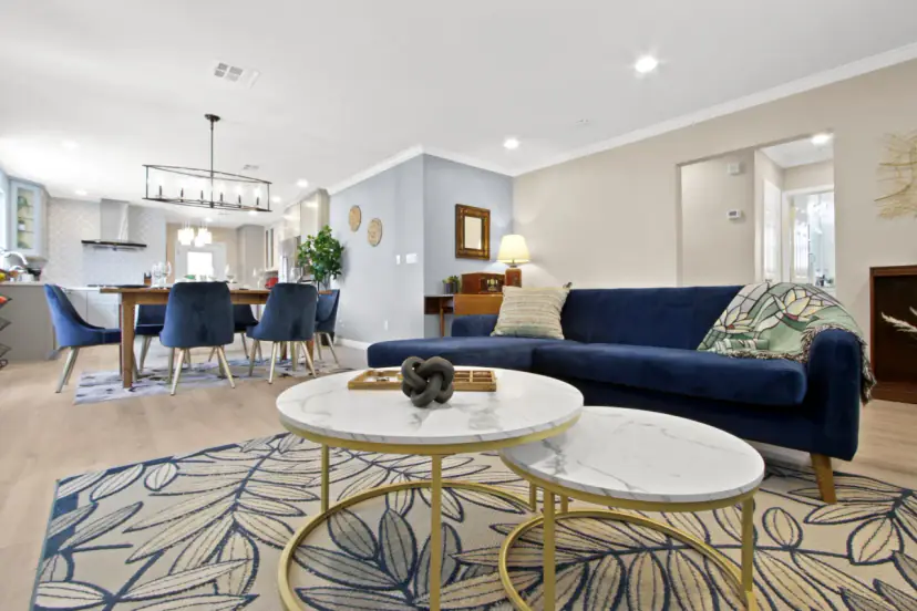 Living and dining room with a navy velvet sofa and round marble coffee tables