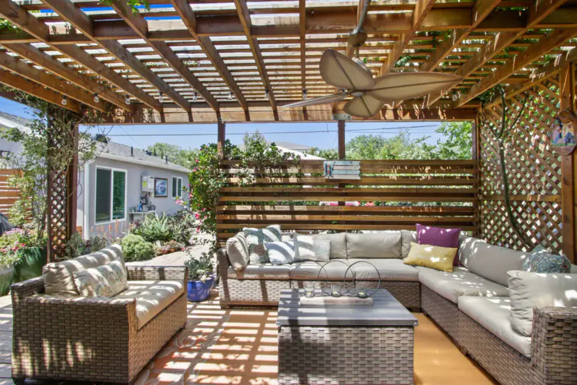 Pergola lounge with wicker sofas and a ceiling fan
