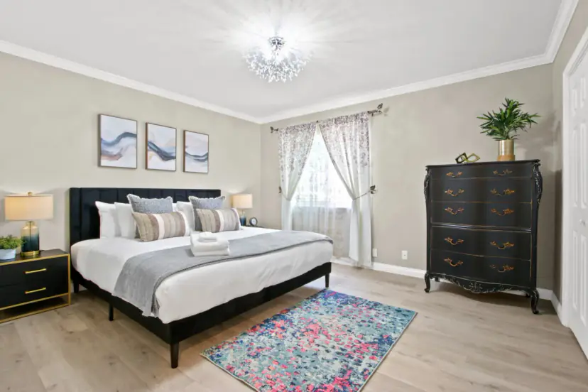 Bedroom with a black bed, a dresser and a patterned rug