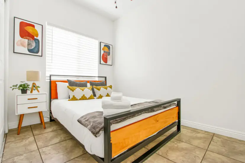 Bedroom with a wood and metal bed and colourful prints