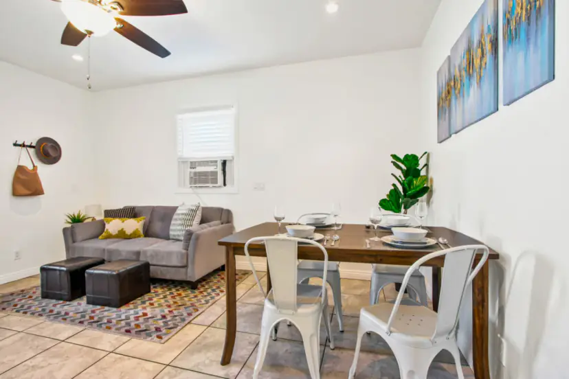 Living room with a grey sofa, ottomans and a dining table for four