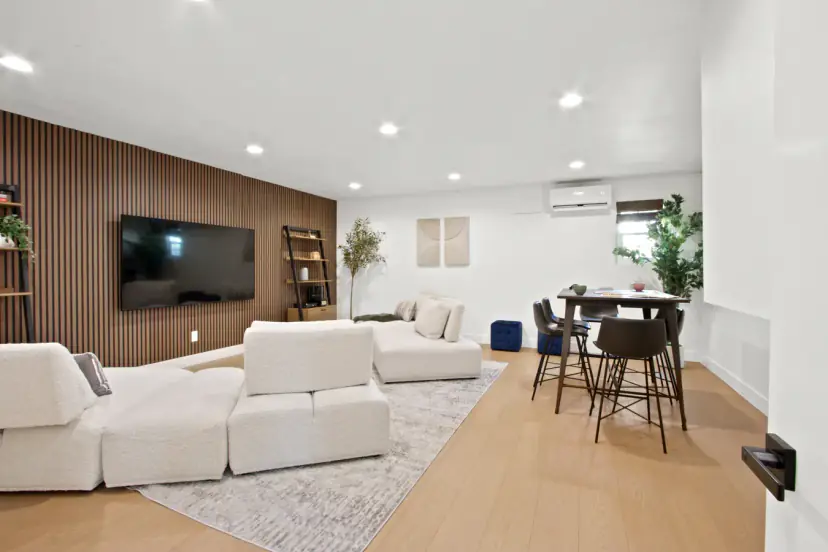Family room with a cream modular sofa, a wall TV and a bar table