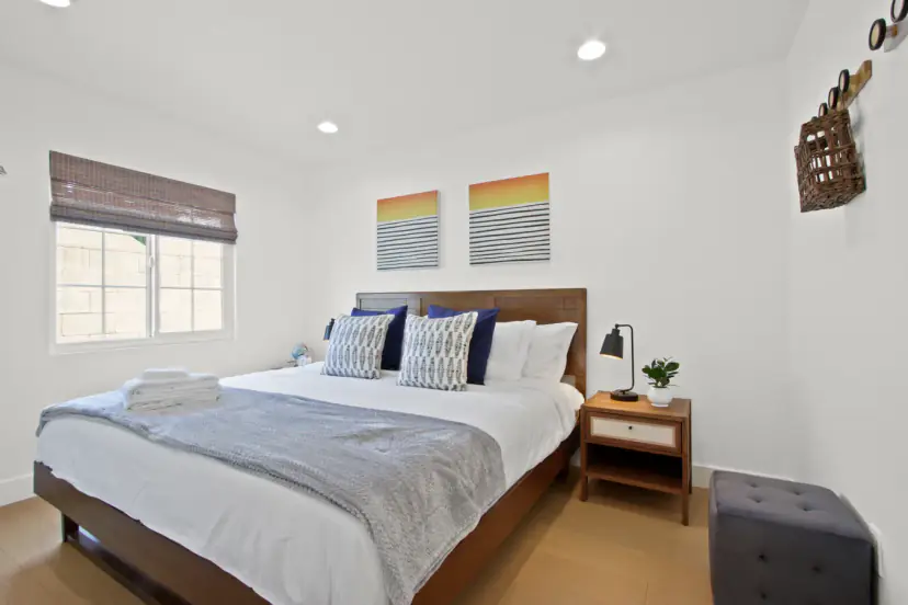 Bedroom with a wood bed, navy pillows and two sunset prints