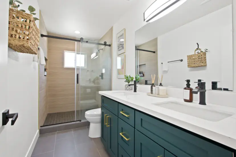 Bathroom with a green double vanity and a glass shower