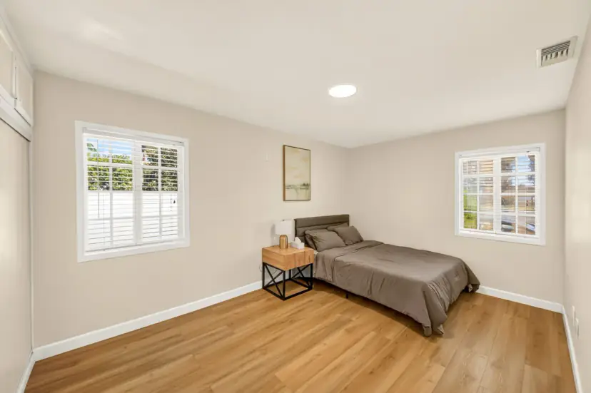 Bedroom with two windows and a wood-frame bed