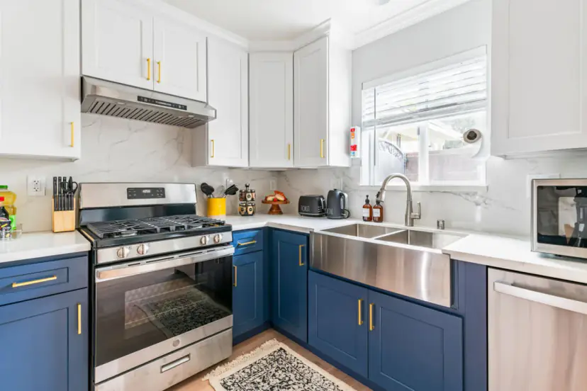 Kitchen with navy lower cabinets, brass pulls, a farmhouse sink and a gas range