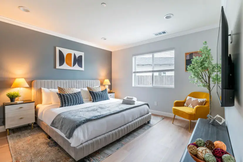 Bedroom with a grey channel-tufted bed, a graphic print and a mustard chair