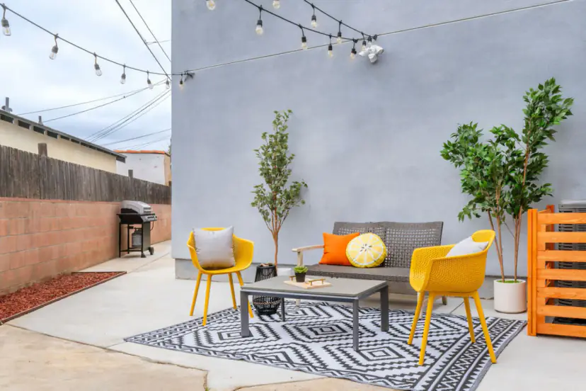 Patio lounge set with yellow chairs on a black and white rug under string lights