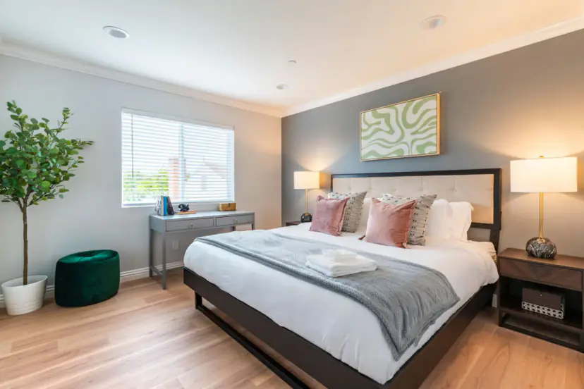 Bedroom with a tufted bed, pink pillows and a wavy green print