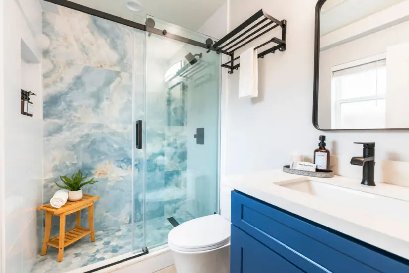 Bathroom with a navy vanity and a blue onyx-look shower behind glass