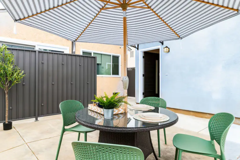 Patio table with green chairs under a striped umbrella