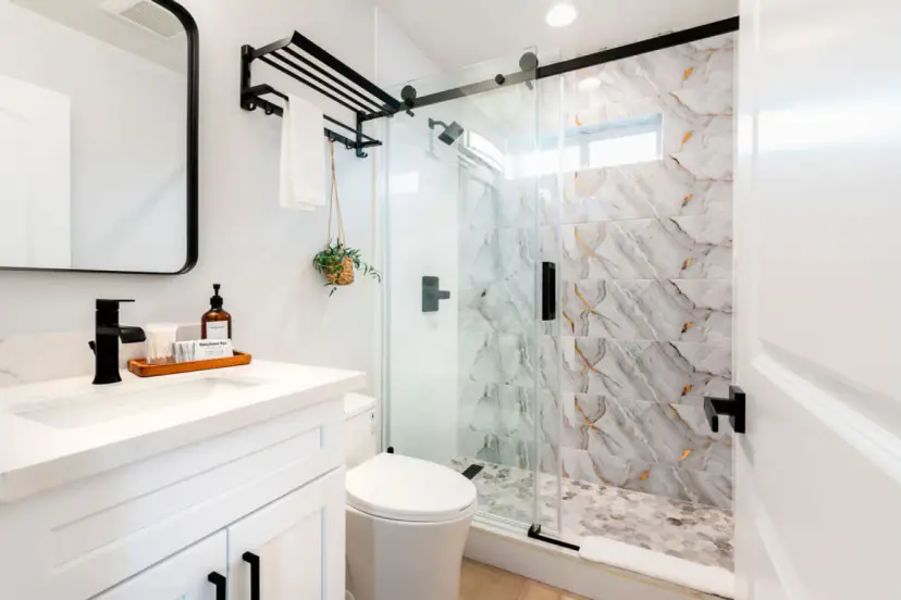 Bathroom with a marble-look shower, black fixtures and a white vanity