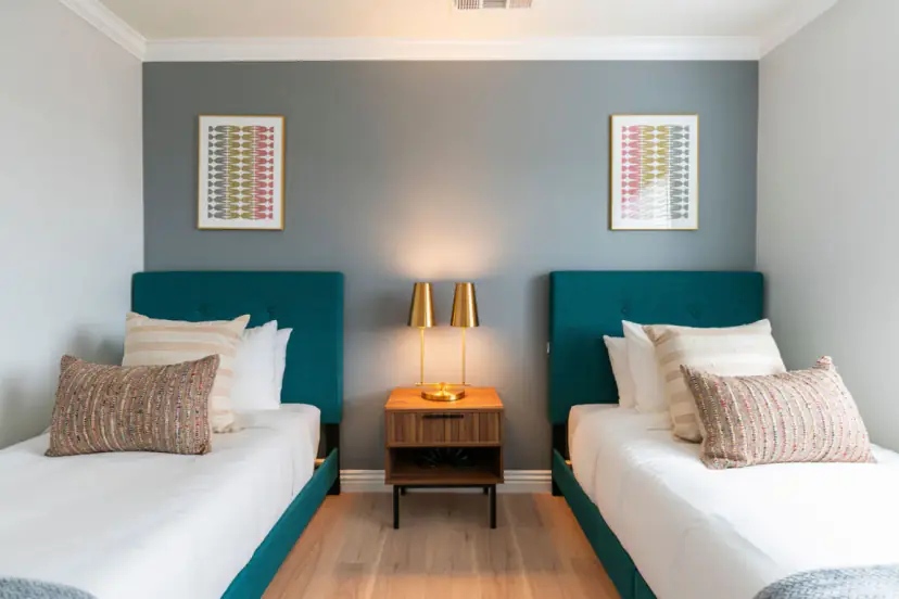 Twin bedroom with teal headboards and gold lamps