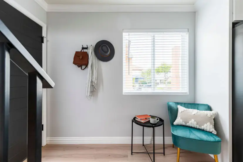 Entry corner with a teal velvet chair and a side table
