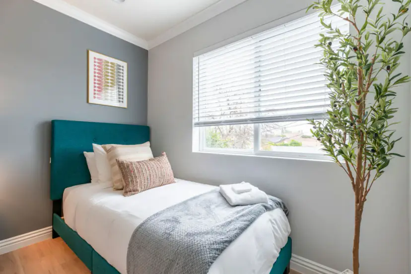 Twin bedroom with teal beds and a window