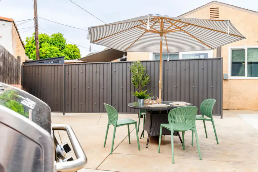 Patio dining set with a grill and a striped umbrella
