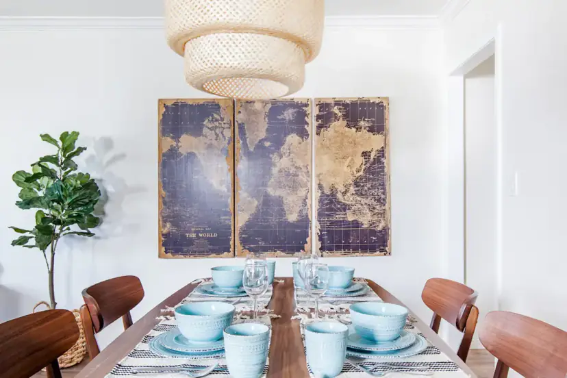 Dining table under a rattan pendant with world-map art
