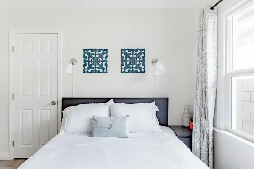 Queen bed with teal carved wall panels and sconces