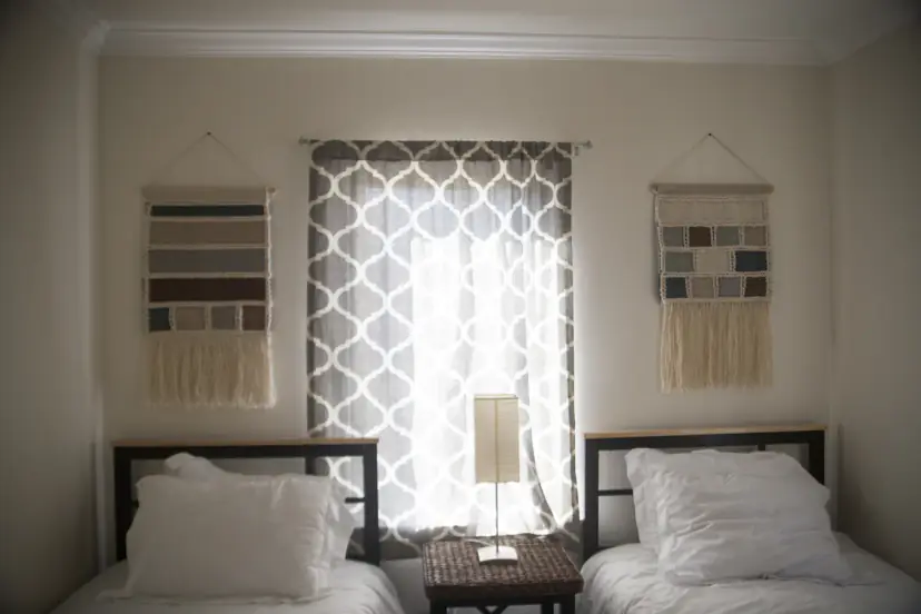 Twin beds with woven hangings and trellis curtains