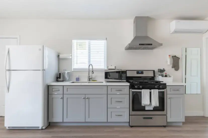 Kitchen with grey cabinets, a gas range and a white fridge