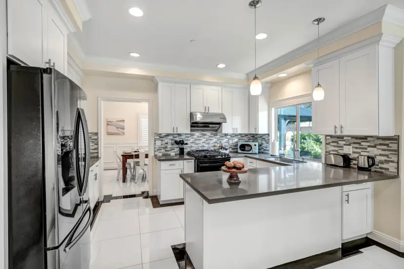 White kitchen with a peninsula counter, pendant lights and a gas range