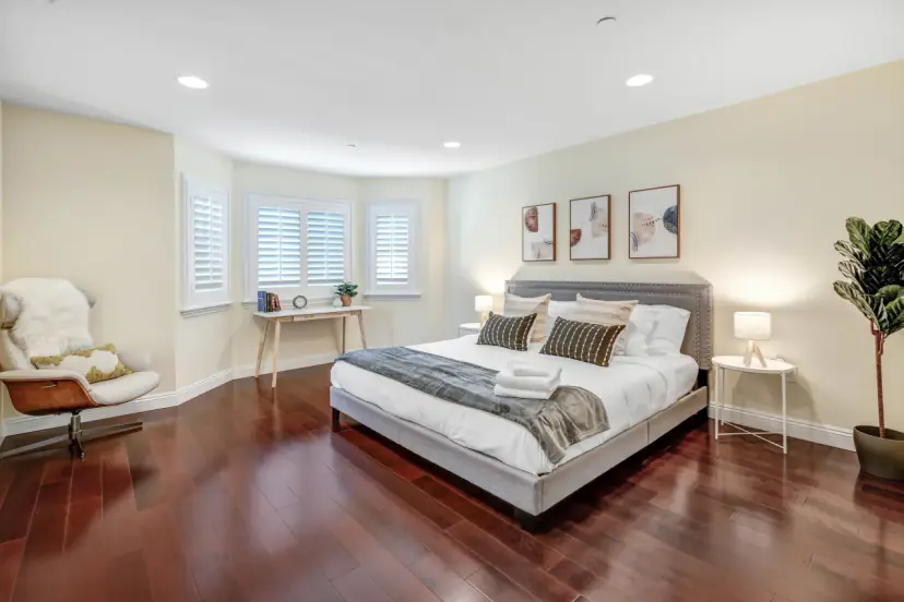 Bedroom with an upholstered bed, wood floors and a lounge chair