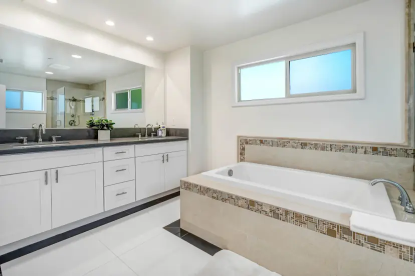 Main bathroom with a soaking tub, a double vanity and mosaic tile trim