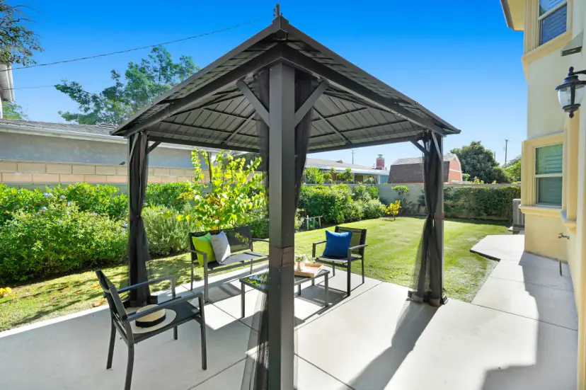 Backyard gazebo with patio chairs and a lawn