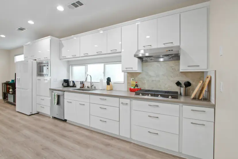 Long white kitchen with a gas cooktop and a microwave wall