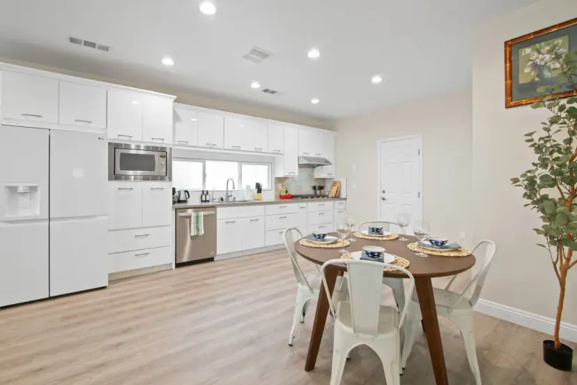 Round dining table with white bistro chairs beside the kitchen