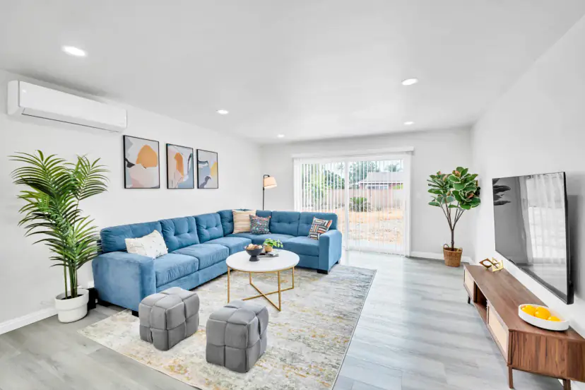 Living room with a blue sectional, ottomans and a wall TV