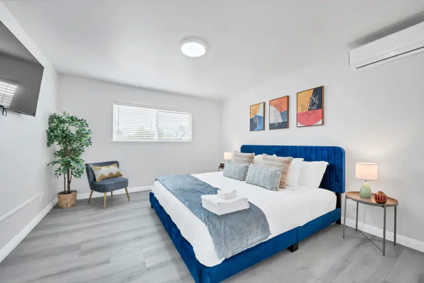 Bedroom with a blue velvet king bed and a wall TV